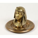 AN EGYPTIAN REVIVAL BRASS INKWELL, modelled as a bust of a pharaoh, on a circular base. 7.5ins