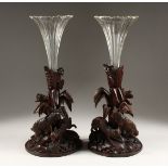 A GOOD PAIR OF BLACK FOREST CARVED WOOD VASE STANDS, one carved as a pair off rabbits, the other a