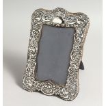 A REPOUSSE SILVER PHOTOGRAPH FRAME with birds 8ins x 5ins