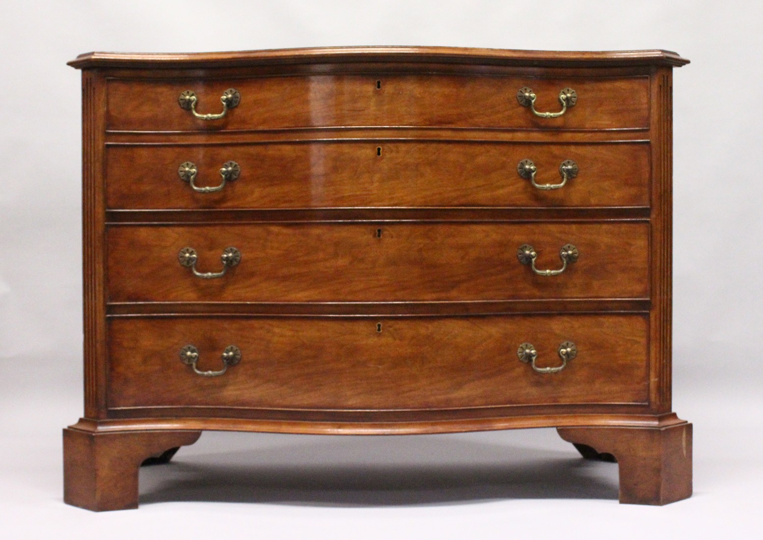 A GEORGE III DESIGN SERPENTINE FRONTED MAHOGANY COMMODE with four graduated long drawers, fluted