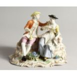 A GOOD FUSTENBURG PORCELAIN GROUP OF A YOUNG MAN AND GIRL ON A BENCH, fruiting vines in a basket