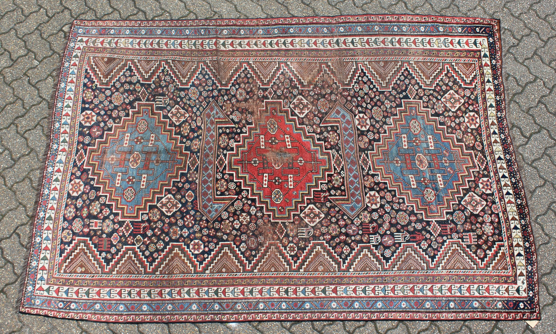 A SHIRAZ RUG, with three large central medallions, in a narrow border. 8ft 7ins x 5ft 9ins.