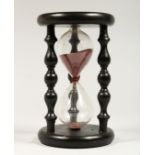 A SAND TIMER IN AN EBONISED STAND 8ins high