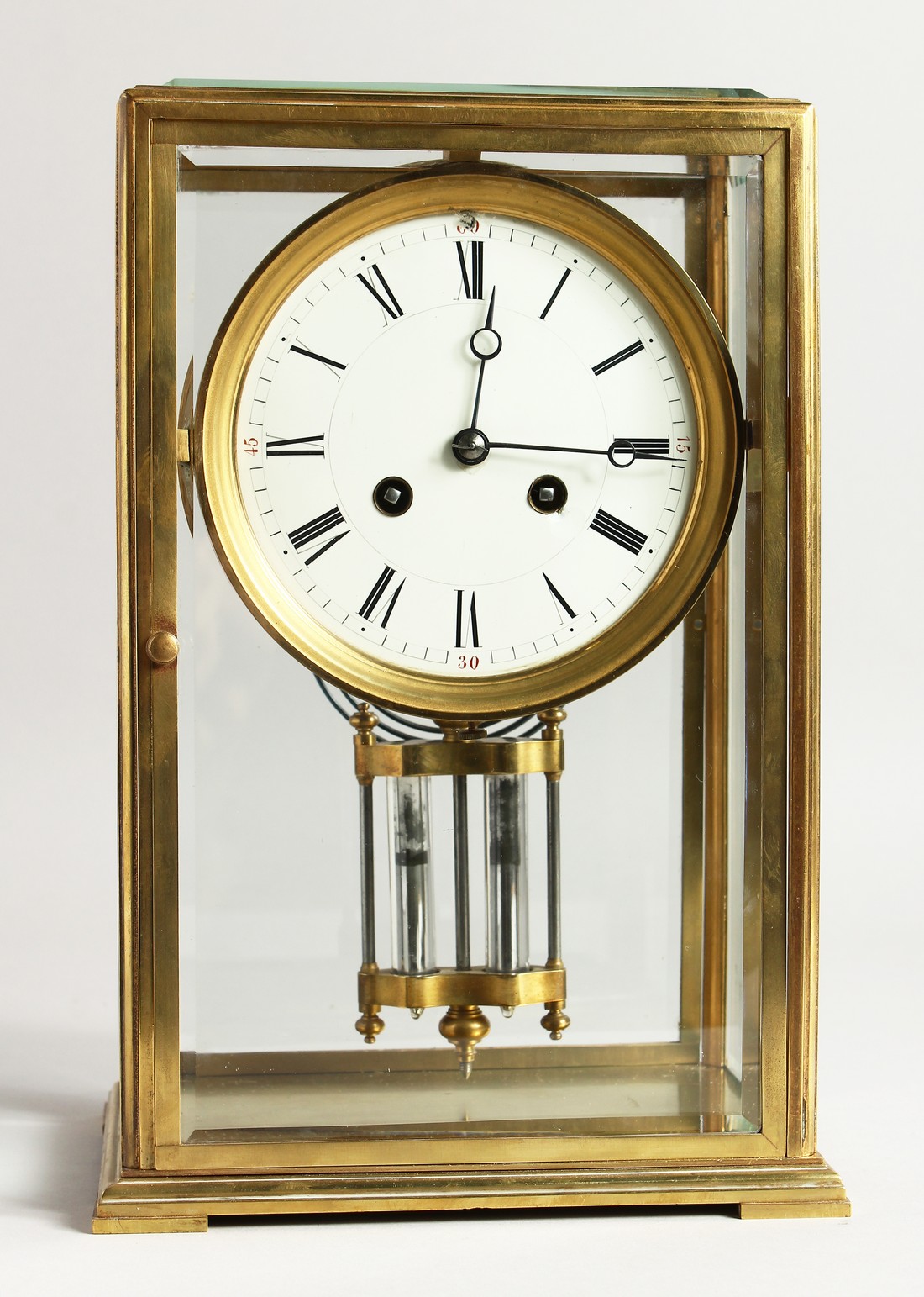 A GOOD BRASS FOUR GLASS CLOCK with white dial and pendulum. 12ins high.