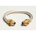 A TWISTED SILVER TORQUE STYLE BANGLE, set with a pair of cabochon amethysts and six oval peridots.