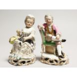 A GOOD PAIR OF MEISSEN PORCELAIN FIGURES, a young man reading a book, a girl sewing. Cross swords