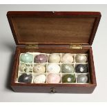 A COLLECTION OF FIFTEEN MINIATURE SPECIMAN STONE EGGS, housed in a mahogany box. Box 6ins long
