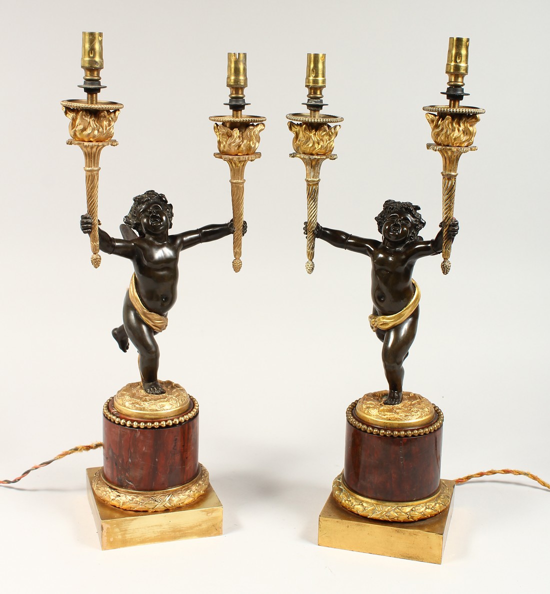 AS VERY GOOD PAIR OF REGENCY BRONZE AND ORMOLU TWO BRANCHED CHERUB CANDLESTICK each holding