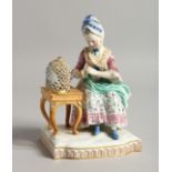 A 19TH CENTURY MEISSEN PORCELAIN GROUP, a seated lady with a bird in a cage. Cross swords mark in