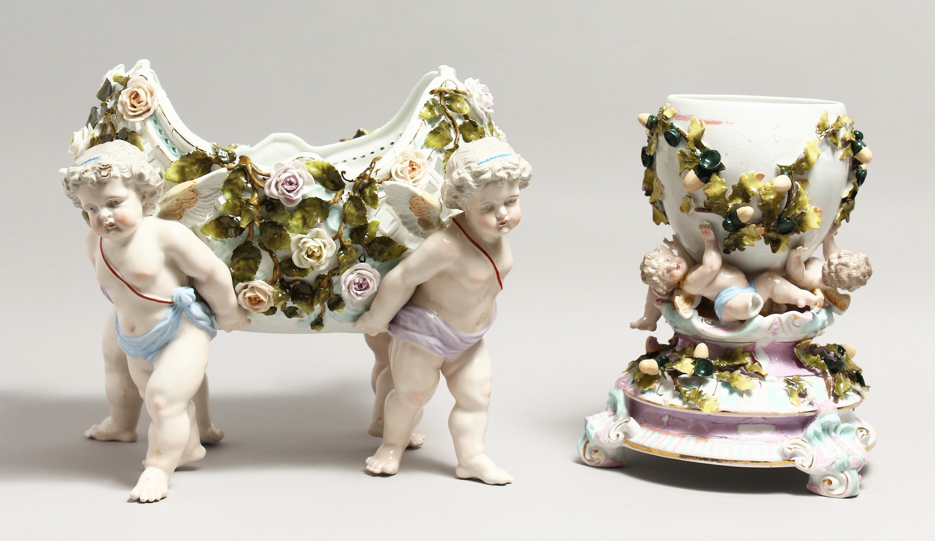 A LARGE FLORAL ENCRUSTED PIERCED PORCELAIN CENTREPIECE of a basket form, being supported by four