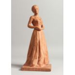 A 20TH CENTURY TERRACOTTA MODEL OF A YOUNG LADY, standing wearing a long dress, indistinctly