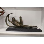 A bronze female reclining nude on a marble plinth base.