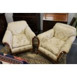 A good pair of upholstered armchairs with carved walnut frames, on claw and ball feet.