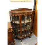 A mahogany bow front display cabinet.