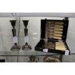 A pair of silver candlesticks and a cased set of plated fish knives and forks.