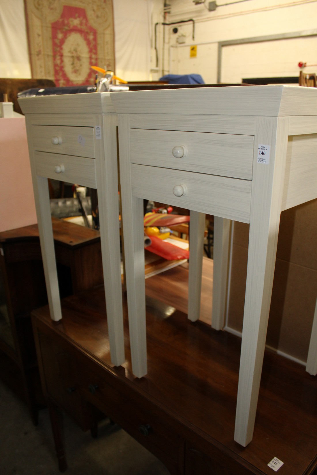 A pair of cream painted bedside tables.