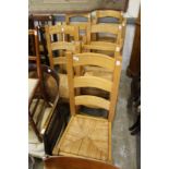 A set of eight modern oak and rush seated ladder back dining chairs.