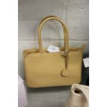 A beige leather handbag with dust cover.