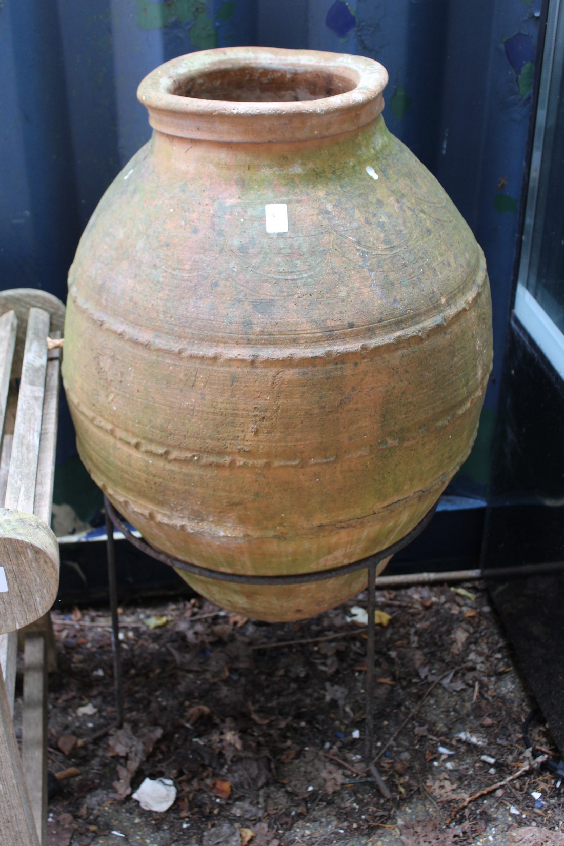 A large terracotta garden urn on a wrought iron stand.