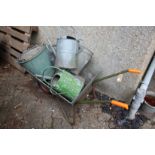 A wheelbarrow and a quantity of galvanized watering cans and buckets.