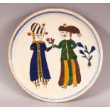 A TURKISH KUTAHYA POTTERY FIGURAL PLATE - decorated with figures and flora, 17.5cm