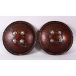 A GOOD PAIR OF INDIAN PAINTED AND LACQUERED LEATHER SHEILDS, each with four glass roundels, 34cm