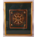 A SMALL FRAMED HAND PAINTED TIBETAN THANGKA, the central circular panel depicting various deities/