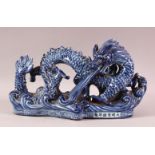 A CHINESE BLUE & WHITE PORCELAIN MODEL OF A SEA DRAGON, depicted rising from the ocean, the front