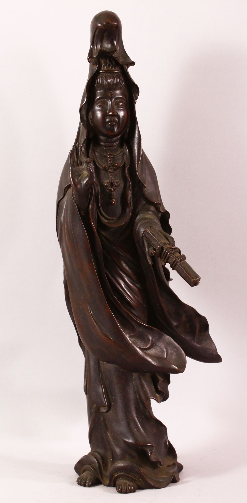 A CHINESE BRONZE FIGURE OF GUANYIN holding a scroll, her other hand raised in a mindfulness gesture,