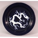 A CHINESE MING STYLE BLUE GROUND PORCELAIN DRAGON DISH, 23CM