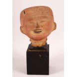 A 17TH/18TH CENTURY EYGPTIAN STONE BUST of a smiling figure in a head dress, elevated on a wooden