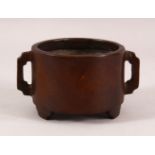 A CHINESE TWIN HANDLE BRONZE BRUSH WASH / CENSER, with twin handles and tripod feet, 14cm diameter