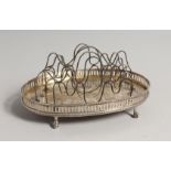 A GEORGE III SILVER OVAL TOAST RACK with wire division on claw and ball feet. London 1774, maker