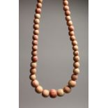 A STAINED IVORY GRADUATED BEAD NECKLACE of forty five beads 13ins long