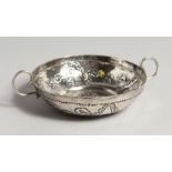 A CIRCULALR WINE TASTER repousse with fruiting vines and plain handles 4ins diameter, makers mark