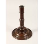 AN 18TH CENTURY TURNED WOOD CANDLESTICK with large circular base 10.5ins high