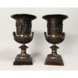 A PAIR OF DECORATIVE CLASSICAL STULE BRONZE TWIN HANDLED URNS, mounted on square flourite bases 14.
