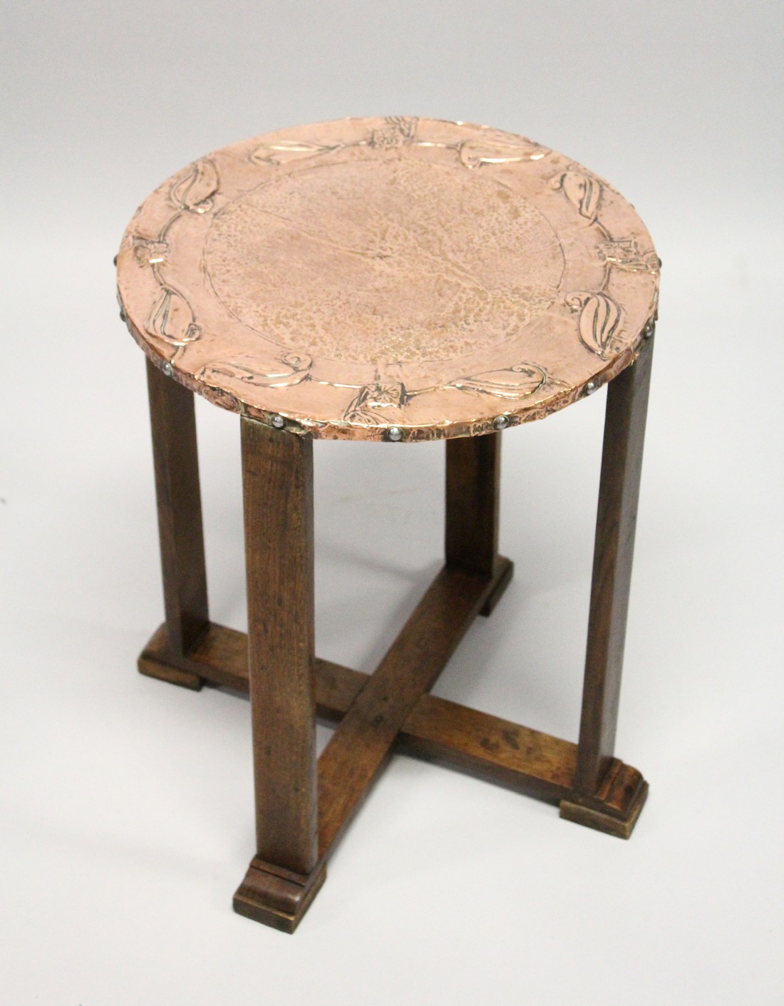 A GOOD ART NOUVEAU COPPER TOP CIRCULAR TABLE on four legs with cross stretchers 1ft 8ins high, 1ft