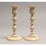 A PAIR OF TURNED IVORY CANDLESTICKS 5.75ins high.