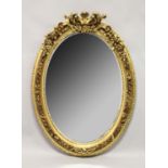 A LARGE DECORATIVE OVAL GILT FRAMED WALL MIRROR. 4ft 2ins high x 3ft wide.