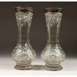 A PAIR OF CUT GLASS VASES with silver top. 12ins high.