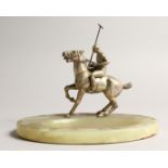 AN ONYX OVAL SHAPED DESK STAND, moulded with a model of a polo player on horseback 8ins wide.