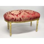 A GILT FRAMED STOOL UPHOLSTERED IN RED DAMASK. 2ft 11ins long x 1ft 8ins wide x 1ft 8ins high.