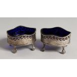 A PAIR OF GEORGE III OVAL SILVER PIERCED ENGRAVED SALTS with a sapphire blue liner on claw and