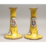 A PAIR OF DRESDEN PORCELAIN CANDLESTICKS, yellow ground painted and gilded with vignettes of a