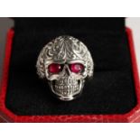 A SILVER SKULL RING with ruby eyes