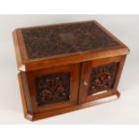 A GOOD VICTORIAN CARVED OVAL TABLE TOP CABINET, the top and doors with carved decoration, the
