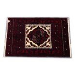 A PERSIAN RUG, 20th Century red ground with a central cream ground panel with stylised decoration.