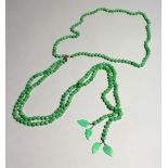 A LONG STRING OF JADE BEADS with gold clasp.