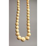 A CARVED IVORY GRADUATED BEAD NECKLACE on fifty three beads 16ins long